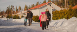 Perhe kävelee Palonummenrinteellä aurinkoisena talvipäivänä. En familj går på Brännmalmsbrinken en solig vinterdag.